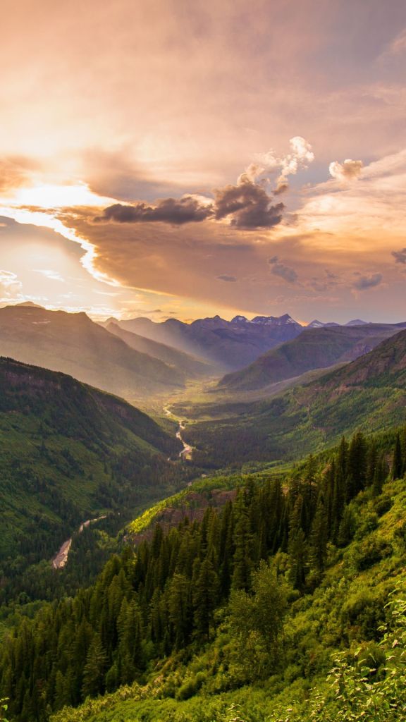 Glowing sunset with light sparkling through the clouds. A luscious mountain range, highlighted by the sunset